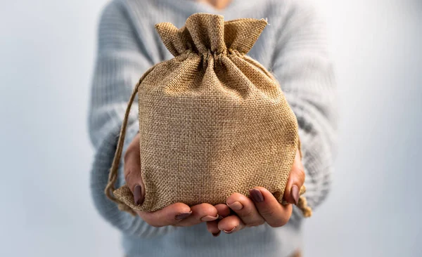 人の中に贈り物を手にバラップバッグを保持 オーガニックテキスタイルで作られた素朴なベージュポーチパッケージを持つ女の子 — ストック写真