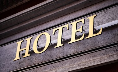 Hotel metal sign on old building facade for tourists. Travel accommodation for night staying reservation clipart