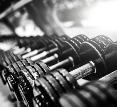 Modern bir spor salonunda arka arkaya metal dambıllar.