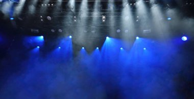 Sahne ışıklarının soyut arkaplanı mavi ve beyaz spot ışıkları ve konser sırasında çalışan sahne sisi