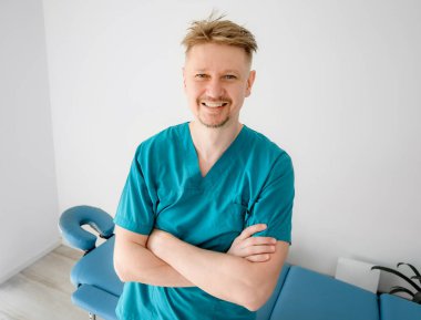 Spa kliniğinde çalışan, gülümseyen ve kameraya bakan profesyonel bir masör. Vücut bakımı kliniğinde tıbbi masaj uzmanı..
