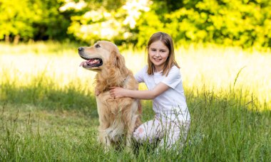 Tatlı kız dışarıda sevimli Golden Retriever köpeğiyle sarılıyor.