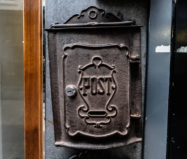 Old retro postal box for letters with design in european city. Antique vintage mailbox on building wall closeup