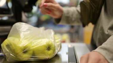 Kız, elinde elma olan plastik bir poşet bekliyor.