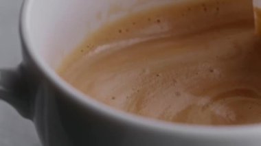 Kahve fincanındaki taze kahve kaşıkla dönüyor.