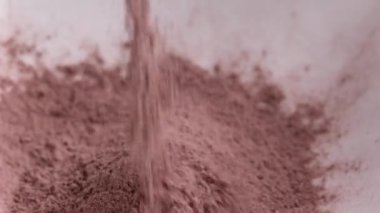 Çikolatalı pasta telaşı için tabağa kakao tozu dökülüyor. Turta fırını için doğal sağlıklı kahverengi gıda malzemesi.