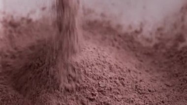 Çikolatalı pasta telaşı için tabağa kakao tozu dökülüyor. Turta fırını için doğal sağlıklı kahverengi gıda malzemesi.