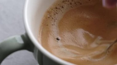 Taze kapuçino hazırlığı için el, süt ve kahve karıştırır. Kabarık köpüklü makroyla kafein latte sıcak içecek.