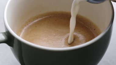 Taze kapuçino hazırlığı için kahve fincanına süt ekliyorum. Sabah kahveli espresso aroma makro manzaralı sıcak içecek.