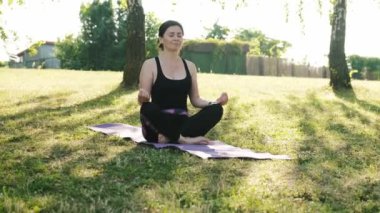 Kız, Lotus pozisyonunda yoga yapmak için yoga minderinde oturuyor. Fitness ve sağlıklı konsept.