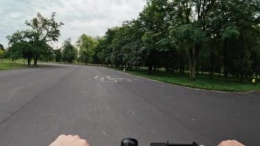 Parkta elektrikli scooter kullanan kız elleri, sürücünün manzarası. Modern hava ulaşımının tadını çıkaran kişi