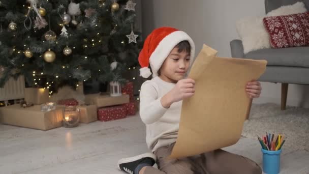 Щасливий Маленький Хлопчик Святковому Капелюсі Дивиться Лист Санта Клауса Сидячи — стокове відео