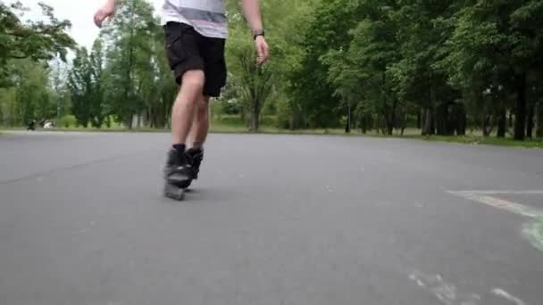 夏に公園で散歩するローラーを練習する若者 ローラーのスケートを身に着けている男はアウトドットの活動を楽しんで 専門的に乗っています — ストック動画