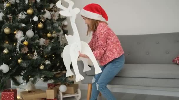 Niña Instalando Figura Reno Papel Bajo Árbol Navidad Junto Perro — Vídeo de stock