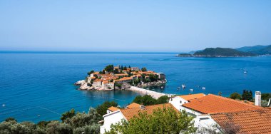 Karadağ 'daki Sveti Stefan adası. Güneşli bir günde lüks tatil köyü ve Adriyatik Denizi manzarası