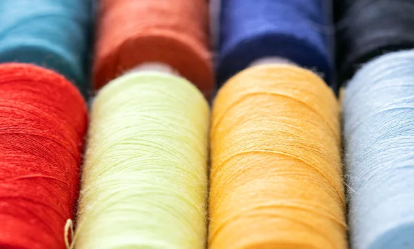 Colorful sewing threads in spools for sew hobby closeup. Macro bobbins for clothing repair