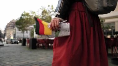 Alman bayrağı ve şehir haritası taşıyan kadın turist Dresden 'deki merkez caddelerde geziniyor.