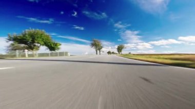 İlk kişi görüntüsü, asfalt yolu üzerinde inanılmaz güneşli manzaralı bir araba yakalıyor.