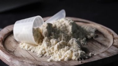 Spor takviyeleri kavramını temsil eden kuru spor proteinleriyle kaşık ölçmek bir tahtada döner.