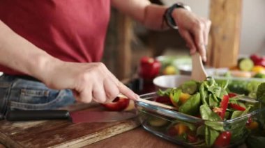 Kız mutfakta sebze salatası pişiriyor ve karıştırıyor. Sağlıklı yemek kavramı.