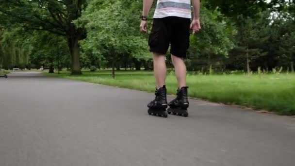 夏に公園で散歩するローラーを練習する若者 ローラーのスケートを身に着けている男はアウトドットの活動を楽しんで 背中からの眺め — ストック動画