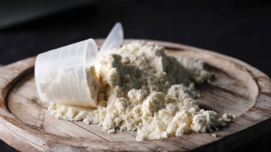 İçinde beyaz protein tozu olan kepçeler, vücut geliştirme ve sağlıklı vücut geliştirme malzemeleri.