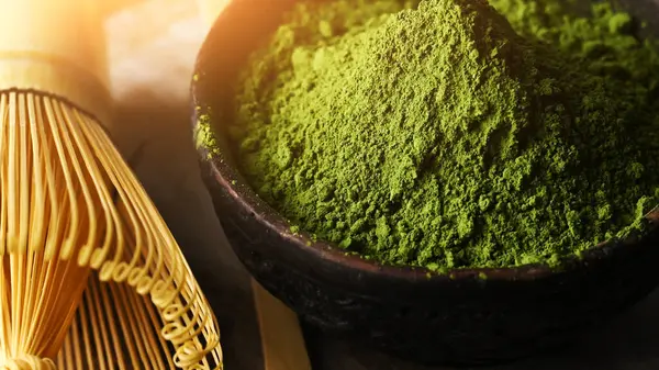 Matcha green tea powder in a bowl with a whisk for whipping