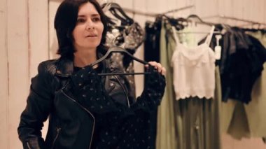 Genç ve çekici bir kadın alışveriş merkezindeki bir giyim mağazasında elbise deniyor.