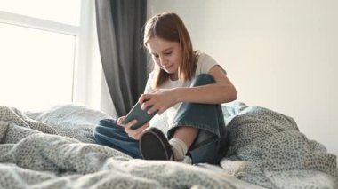 Akıllı telefondan evde yatakta oyun oynayan güzel bir kız çocuğu. Yatak odasında cep telefonu sanal gerçekliği olan genç bayan oyuncu.