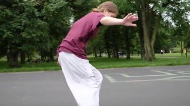 Güzel bir kız parkta sürat yaparak kayak yapıyor. Neşeli genç aktif yaz tatilinin tadını çıkarıyor.