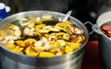 Meyve suyu elmaları ve portakallar. Sokak yiyecek pazarında sıcak sıcak sıcak şarap. Açık hava festivalinde renkli sıcak meyve ve böğürtlen içilir.