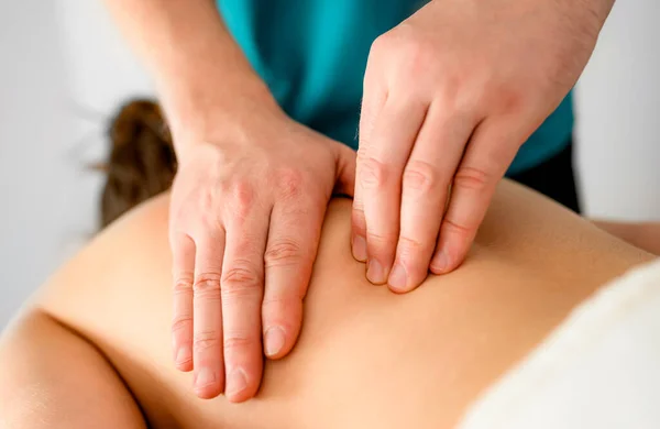 Professional massage therapist doing massage of trigger points in the back in the massage parlor