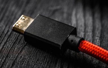 HDMI bağlanıcılı kırmızı kablo, koyu bir masada, görüntüyü kapat