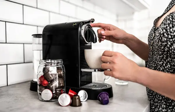 女孩与胶囊咖啡机和杯子在厨房 用专业的浓缩咖啡制造商配制意大利咖啡因饮料的妇女 — 图库照片