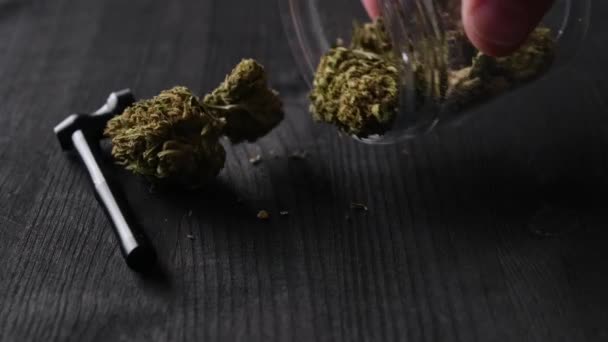 用烟斗从瓶中倒入盛满大麻酚的干大麻大麻花放在桌上 — 图库视频影像