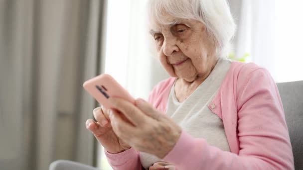 老年妇女滚动智能手机屏幕和在线阅读新闻 — 图库视频影像