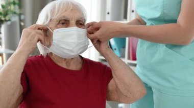 Virüs ve Solunum Hastalıkları Döneminde Hemşire Yaşlı Kadın 'a Koruyucu Maske Giymesinde Yardım Ediyor