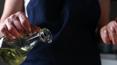 Yemek pişirirken yağ döken kız, sebze yağı bir sürahide dökülüyor.