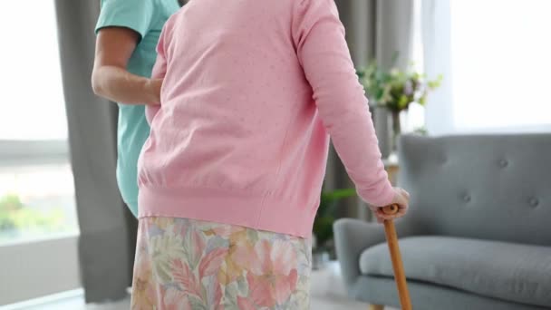 Медсестра Допомагає Старій Жінці Тростиною Сидіти Дивані Світлій Кімнаті — стокове відео