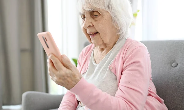 Old Woman Talks Via Video Call Using Smartphone In Home Room