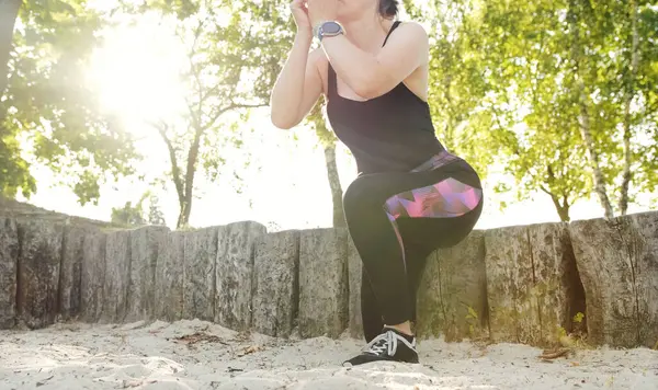 Fitness girl doing squats on the one leg, hip and knee joint muscles training, outdoor recriation