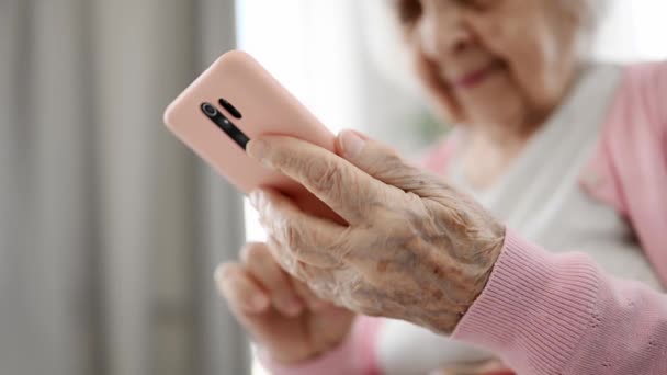 スマートフォン読書インターネットニュースを使用した高齢女性 閉じる ビュー — ストック動画