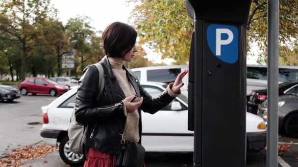 女性は クレジットカードを使用して駐車メーターを介して駐車するために支払います — ストック動画