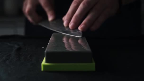 男性の手はウェットストーン 遅い動きのビデオが付いている大きい台所のナイフをシャープにする — ストック動画