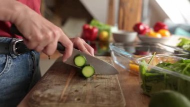 Sağlıklı sebze salatası için mutfakta salatalık kesen bir kız.