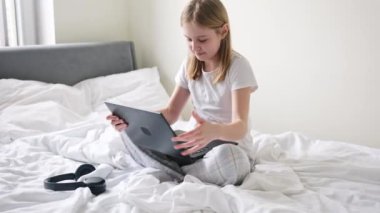 Tatlı küçük kız sabahları kulaklık takıp laptopuyla oynuyor.