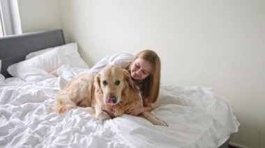 Küçük okul öncesi kızı yatağında altın bir köpekle oynuyor.