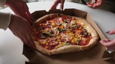 Eller kutudan pizza alıyor, aile pizza yiyor.