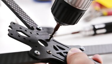 DIY fpv drone çerçevesi monte ediliyor. Helikopter gövdesinin vidaları sıkışıyor, yakın çekim görüntüsü.