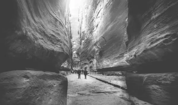 游客们在约旦佩特拉附近令人惊奇的巨大岩石峡谷中漫步 黑白照片 — 图库照片